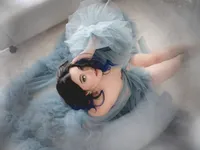 Overhead portrait of a dark-haired woman lying in pale blue tulle, fine art boudoir photography
