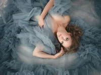 Woman in a dusty blue tulle gown lying on the floor, overhead fine art boudoir portrait in Long Beach