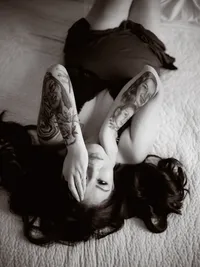 Dark-haired woman in lingerie lying on white fur, moody fine art boudoir portrait