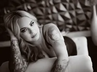 Black and white portrait of a tattooed woman in lingerie leaning on a sofa, Long Beach boudoir photography