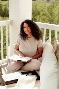 woman sitting on a bench holding her journal smiling