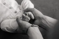 Elternhände halten Babyfüsse – emotionale Newbornfotografie in Schwarz-Weiss