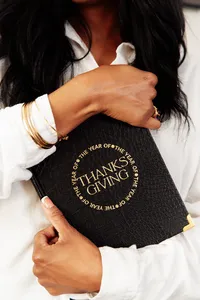 woman holding black the year of thanksgiving journal