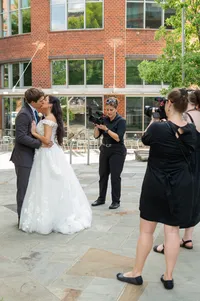 A newlywed couple kissing and being photographed