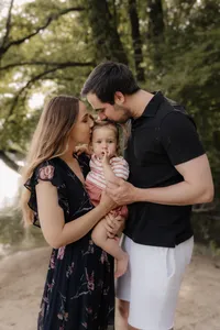 Familie küsst ihr Kleinkind am Fluss – emotionale Familienfotografie im Abendlicht