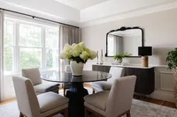 Sleek dining room project designed by Glass House Design Group in Boston. glass table with a big yellow flower bouquet and cream fabric chairs. Effortlessly chic New England interior design that works for real life.