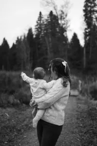 Natürliche Familienfotos im Aargau – Mutter trägt ihr Baby auf einem Waldweg