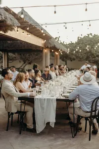 Guests sitting at a wedding table with white linens and bistro lights overhead