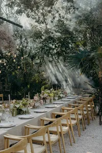 Tablescape in the jungle with light wooden chairs and pink pastel flowers
