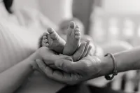 Babyfüsse in schützenden Elternhänden – liebevolle Newbornfotografie in Schwarz-Weiss
