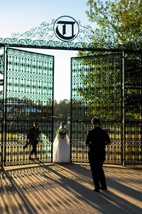 Photographers taking pictures of a newlywed couple in a grand gate