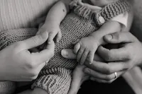 Elternhände berühren zarte Babyhände – emotionale Newborn Homestory in Schwarz-Weiss