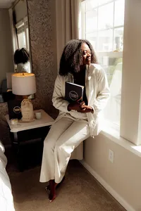 woman sitting on window sill holding her journal