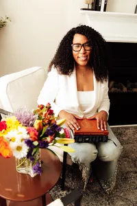 woman sitting in a chair smiling holding her the year of thanksgiving journal