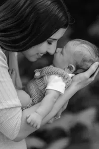 Mutter hält ihr Neugeborenes Stirn an Stirn – innige Newbornfotografie in Schwarz-Weiss