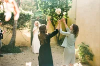 Bridesmaids tossing wedding bouquet outdoors while bride watches