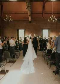 Bride walking down the aisle at a brick-walled indoor wedding venue