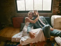 Bride and groom relaxing on couch indoors, embracing each other
