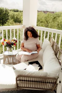 El elyon print co. founder Lindsey sitting outside reading and writing in her year of thanksgiving journal
