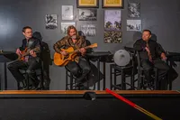 a band sitting in hightop chairs playing together