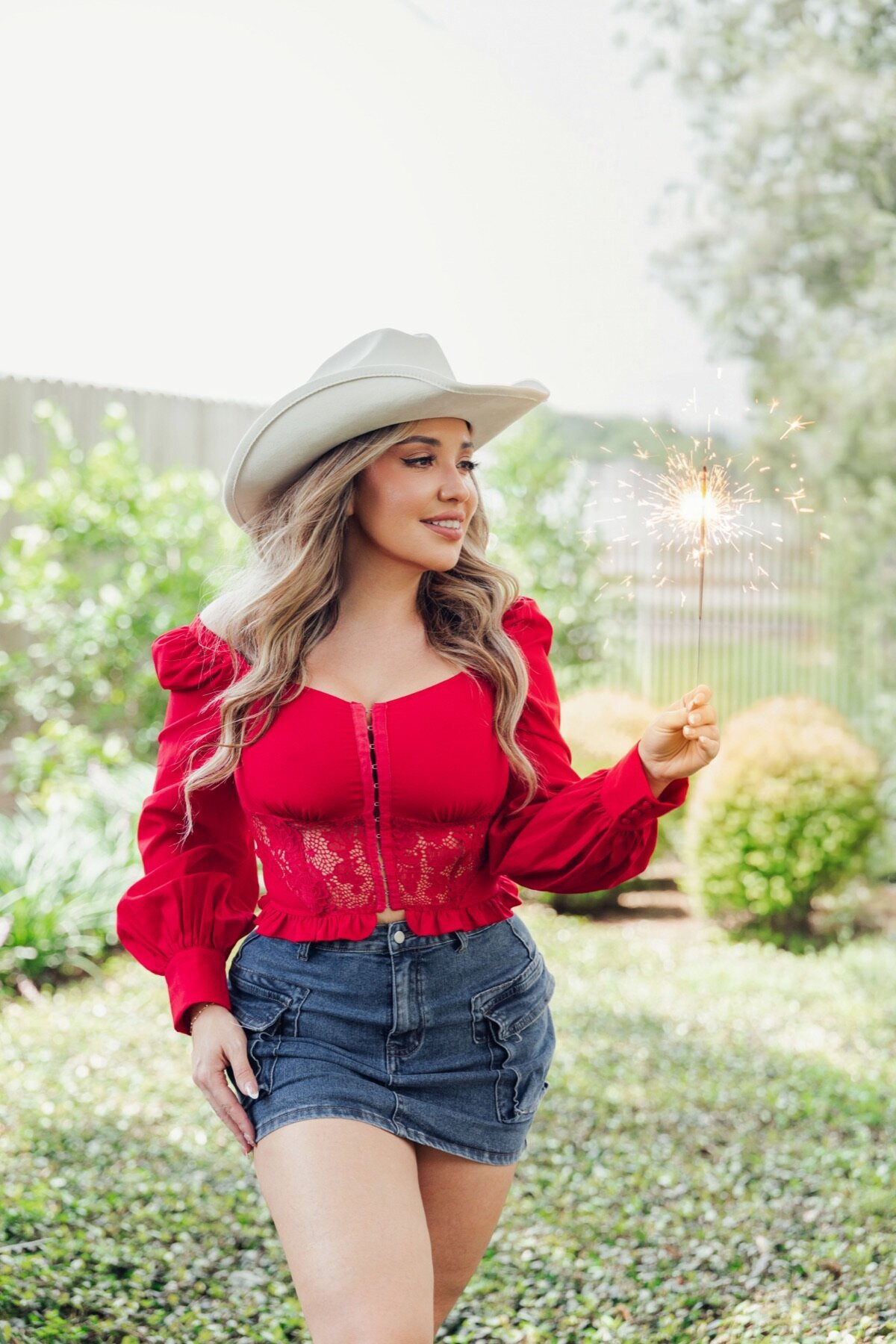 Woman in a white cowboy hat and American flag looking up