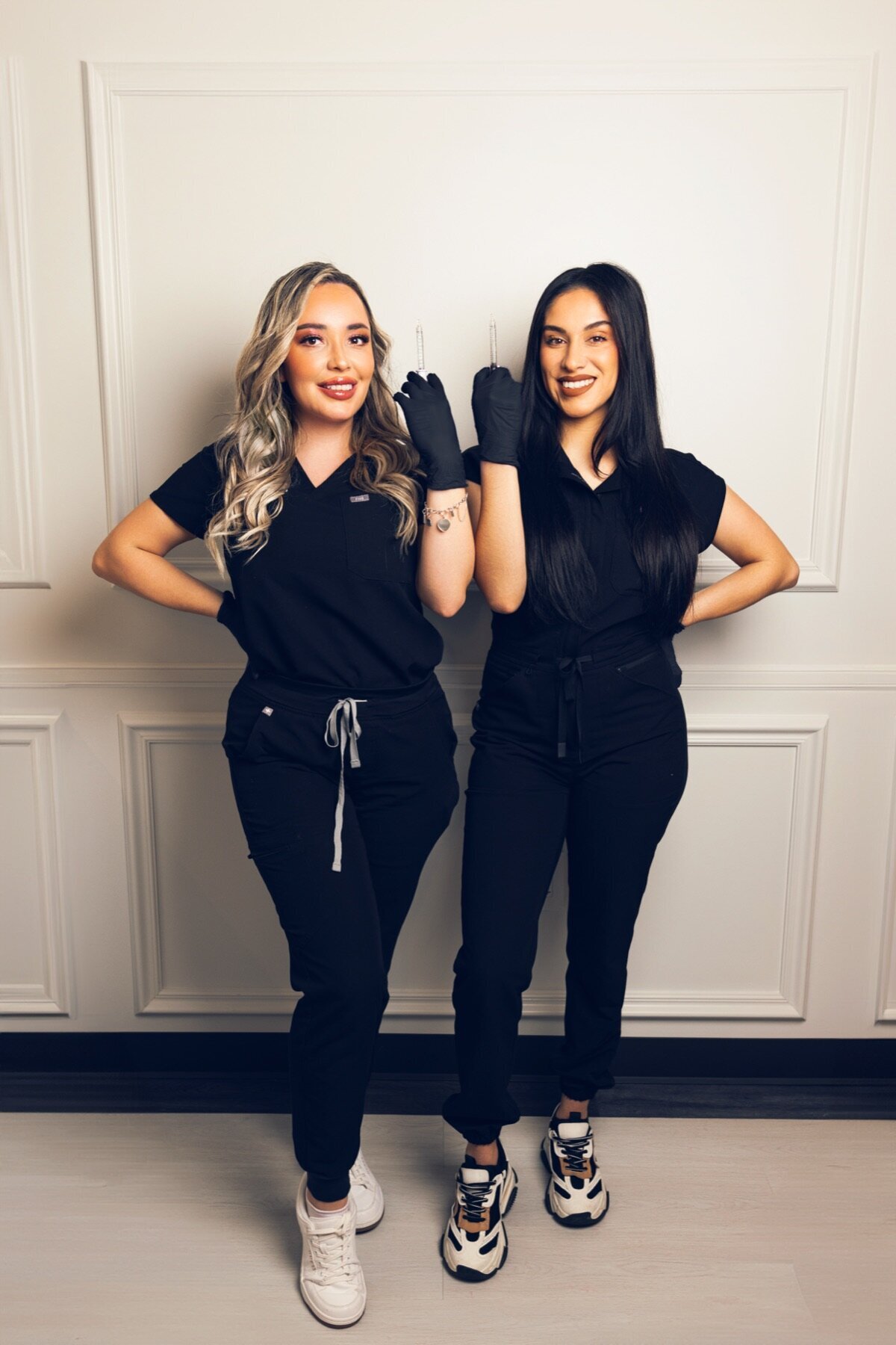 Two team members in black scrubs posing playfully