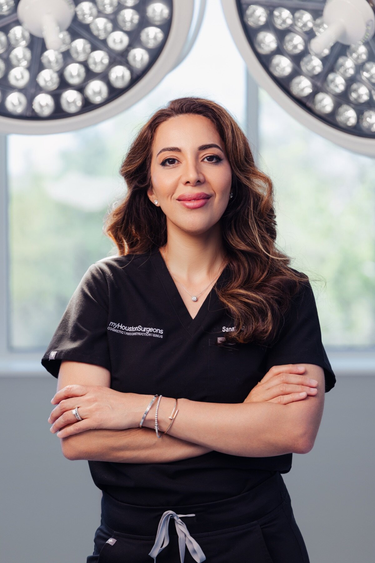 Surgeon in black scrubs with arms crossed in an operating room