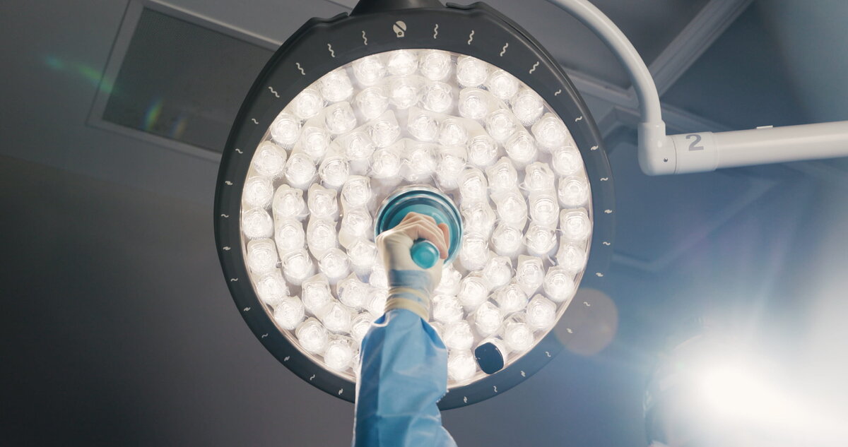 Gloved hand adjusting an operating room light