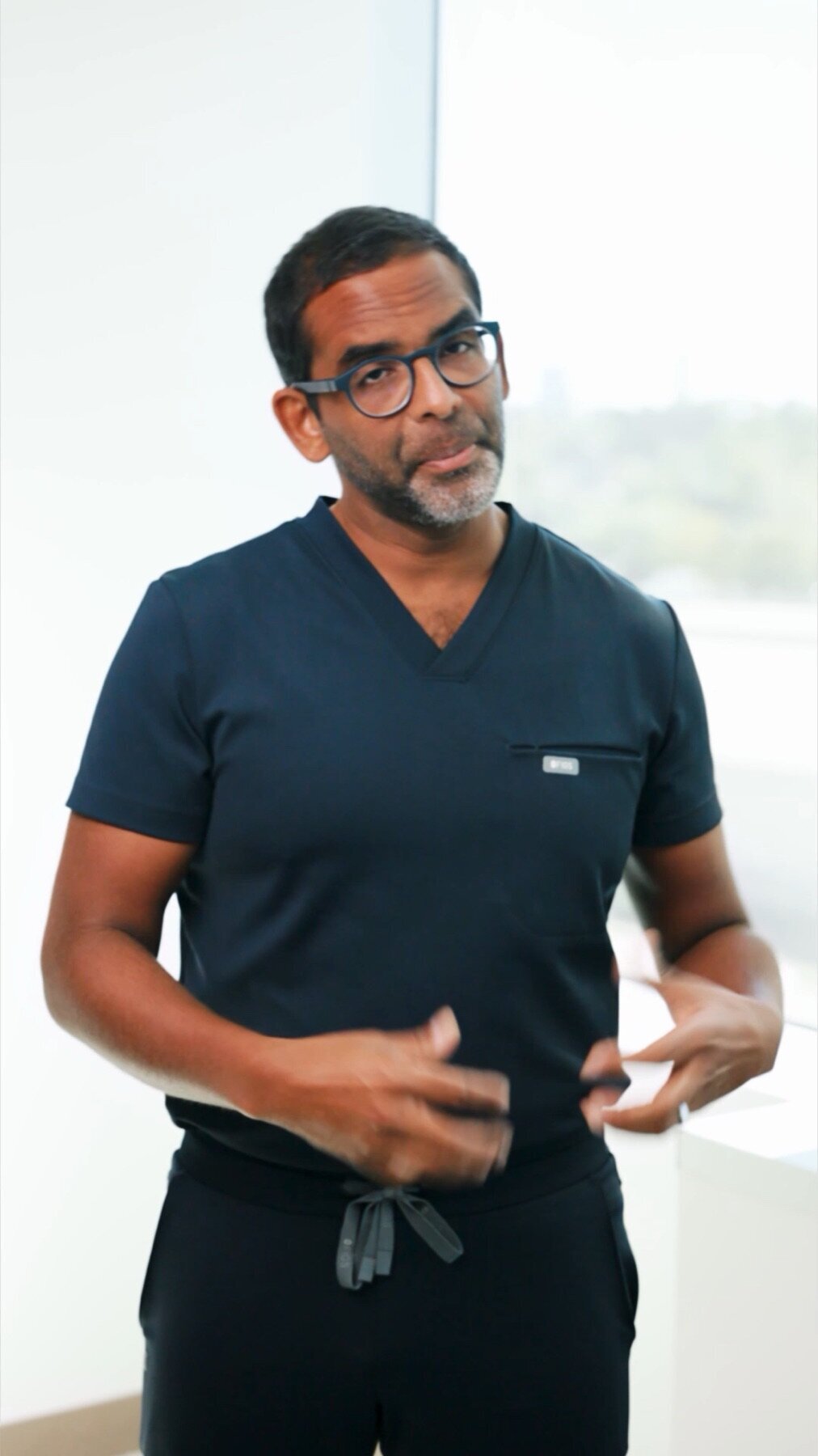 Surgeon in navy scrubs talking by a window