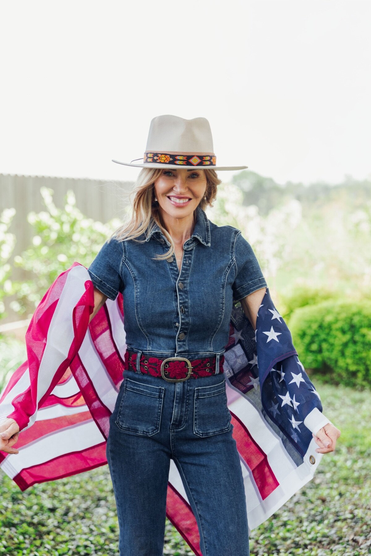 Woman in a white cowboy hat holding an American flag around her shoulders