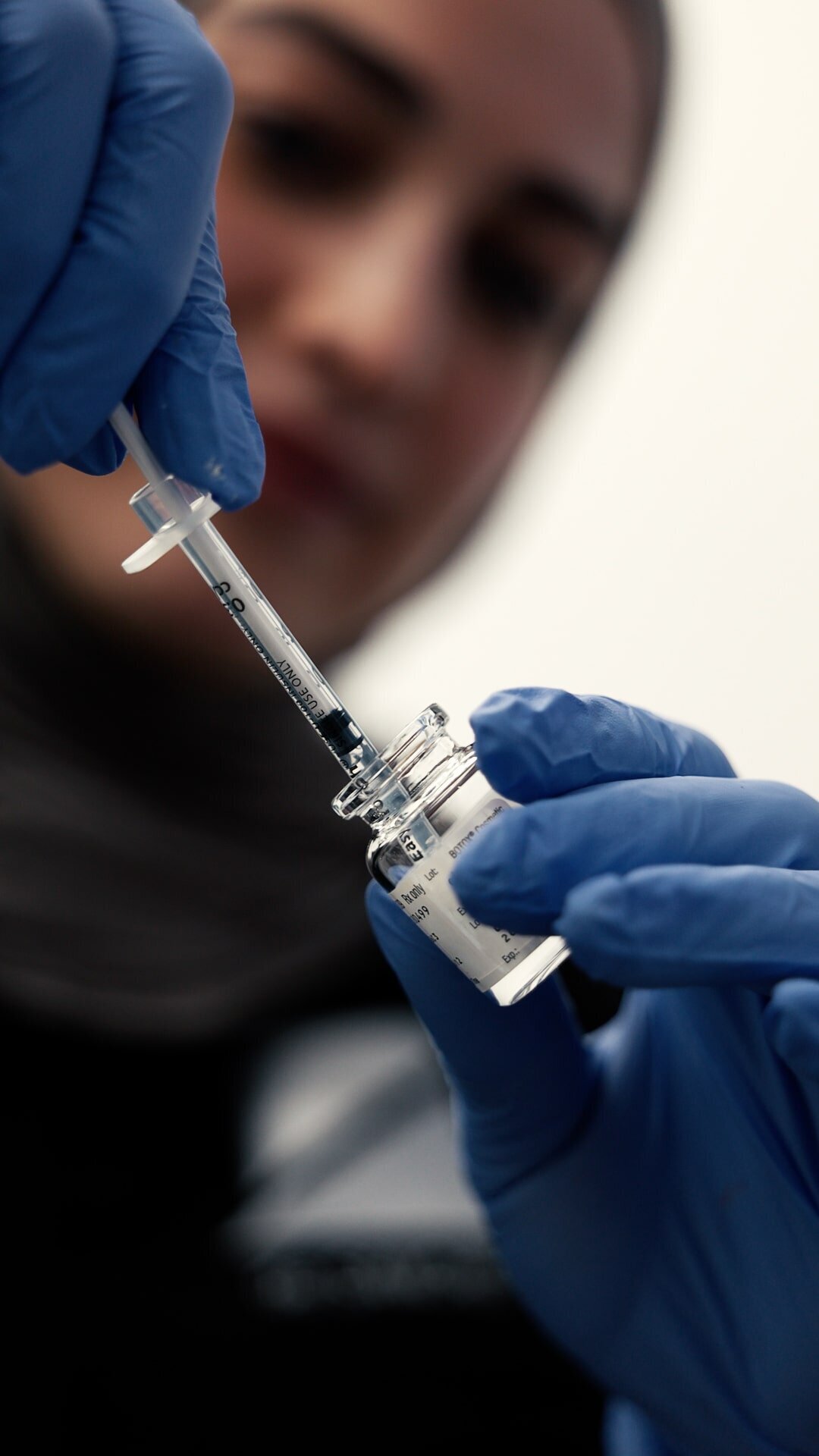 Provider in blue gloves drawing up a syringe