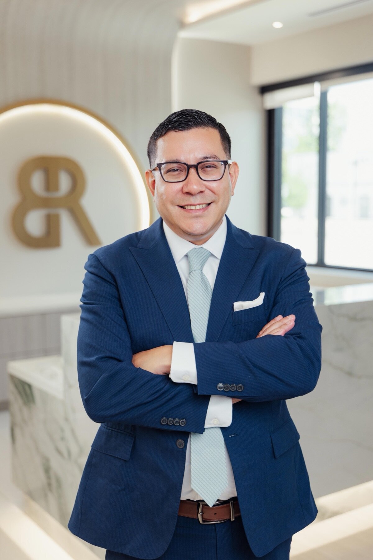 Man in a navy suit with arms crossed in the Body by Ravi lobby