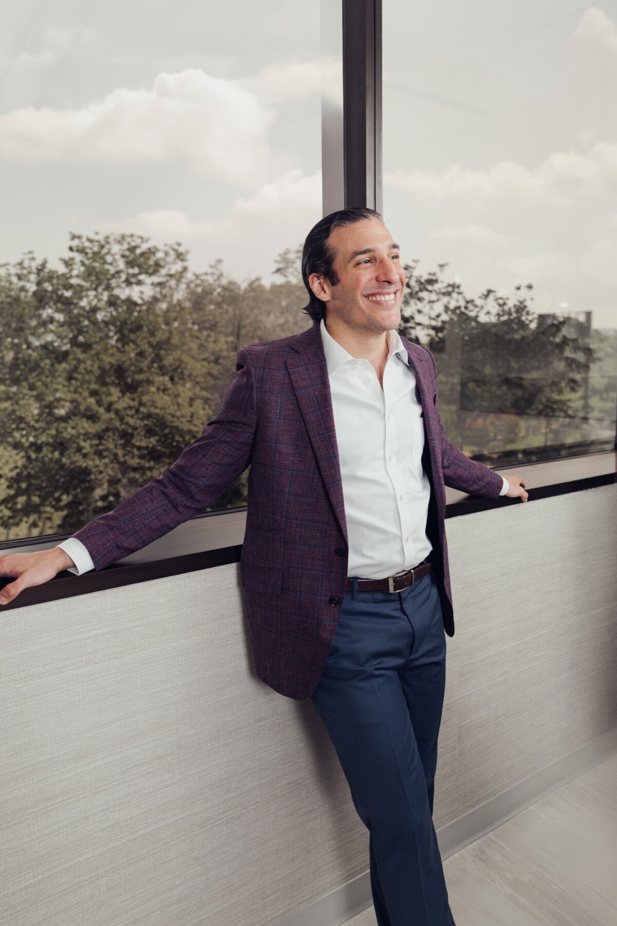 Surgeon in a blazer leaning on a railing outside the practice