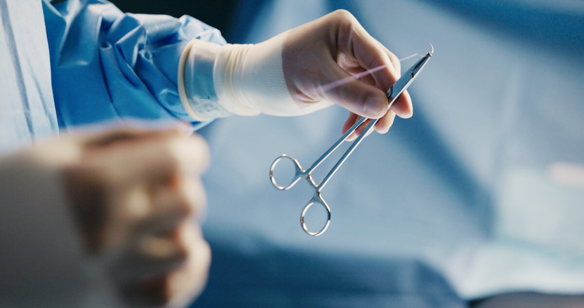 Gloved hand holding surgical forceps