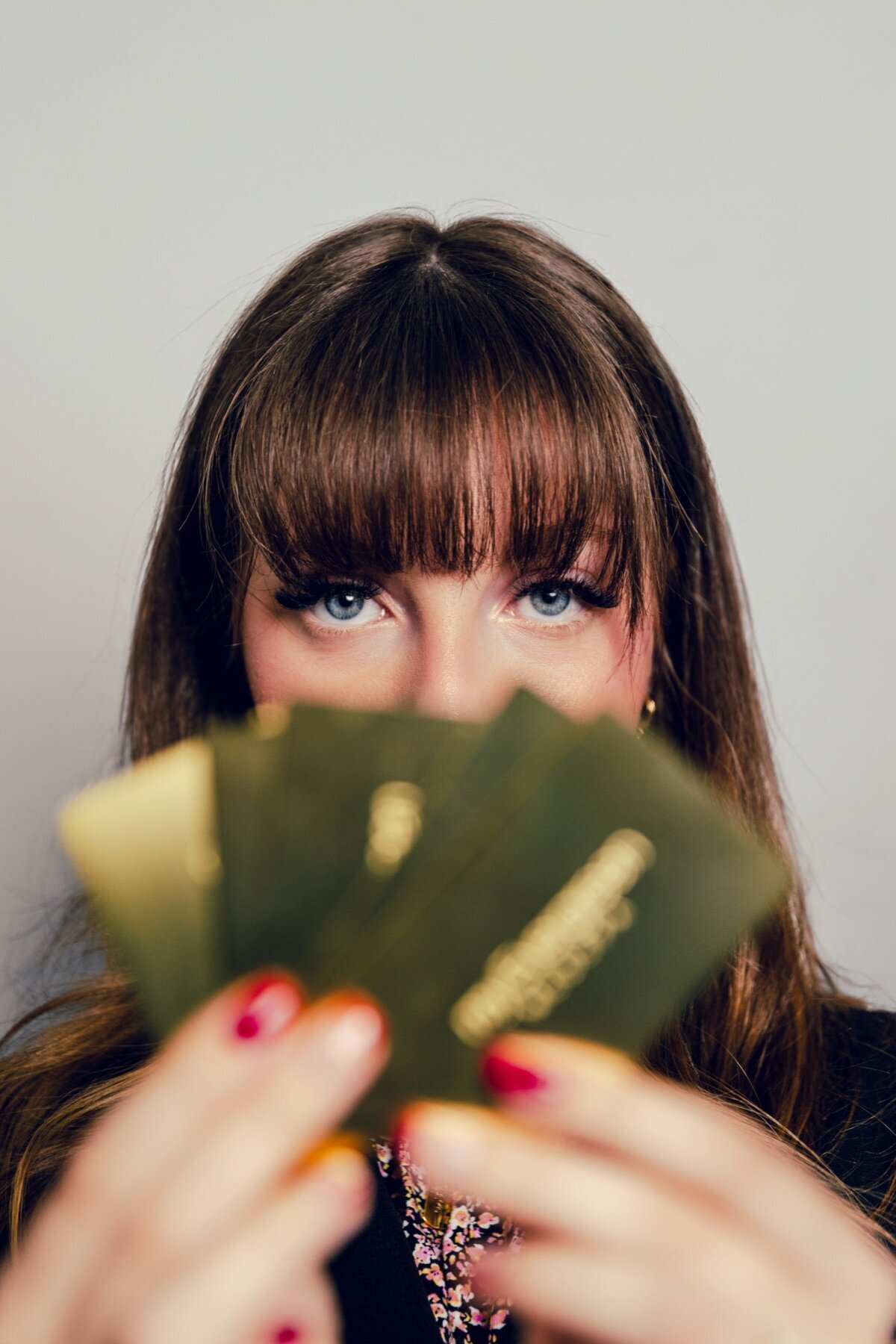 Woman holding gold gift cards in front of her face