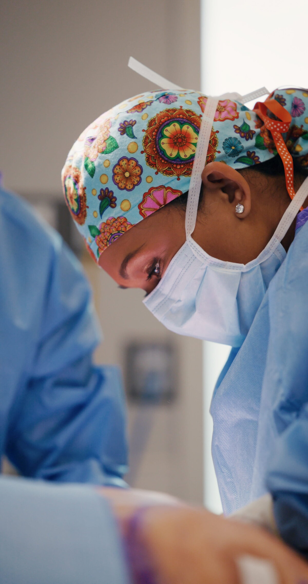 Surgeon in a floral scrub cap and mask during a procedure