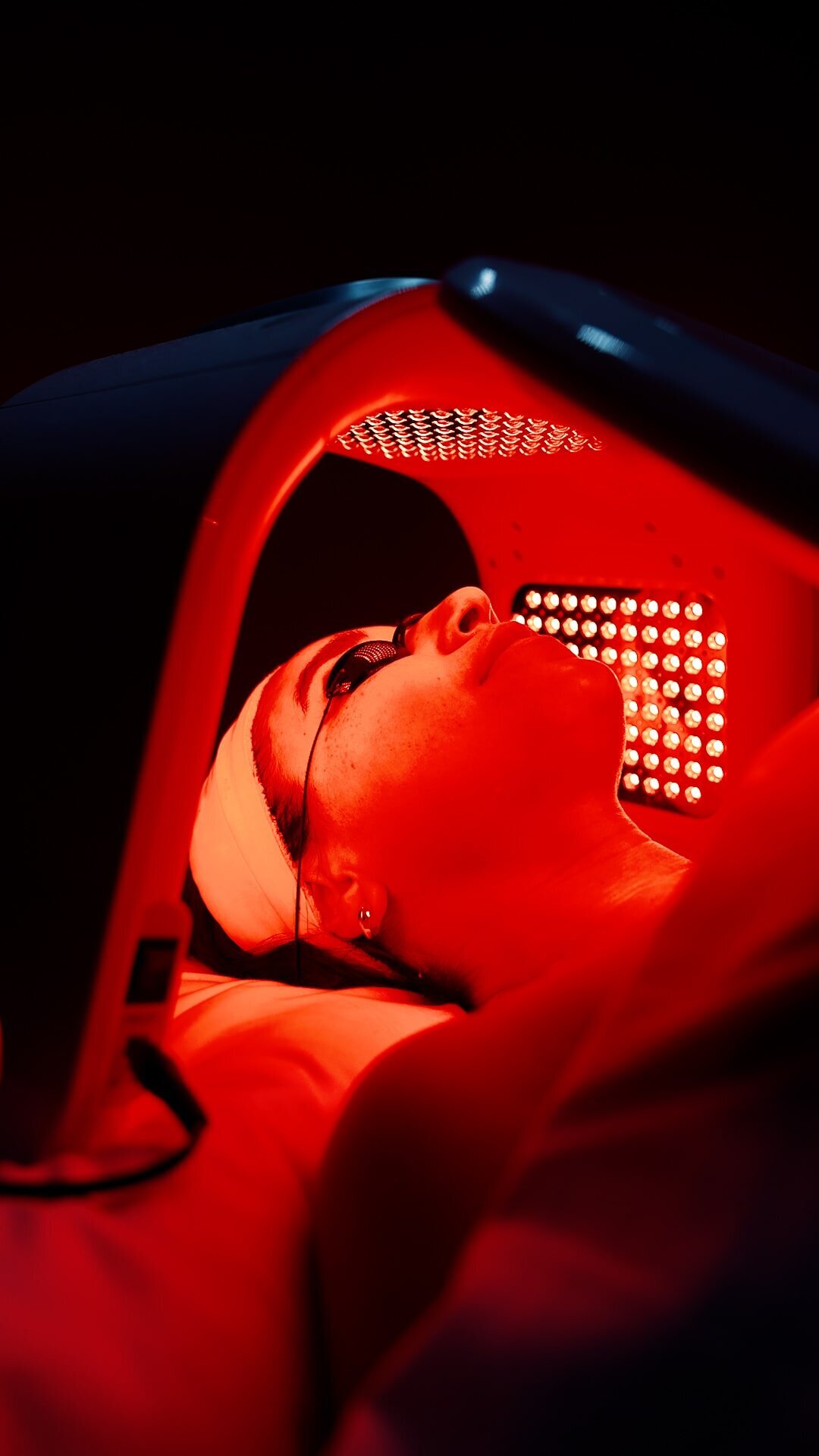 Patient under a red LED light therapy panel