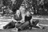 fallback shared on Invalid Date | Black and white image of a joyful family cuddled up on a garden blanket, laughing hearti...