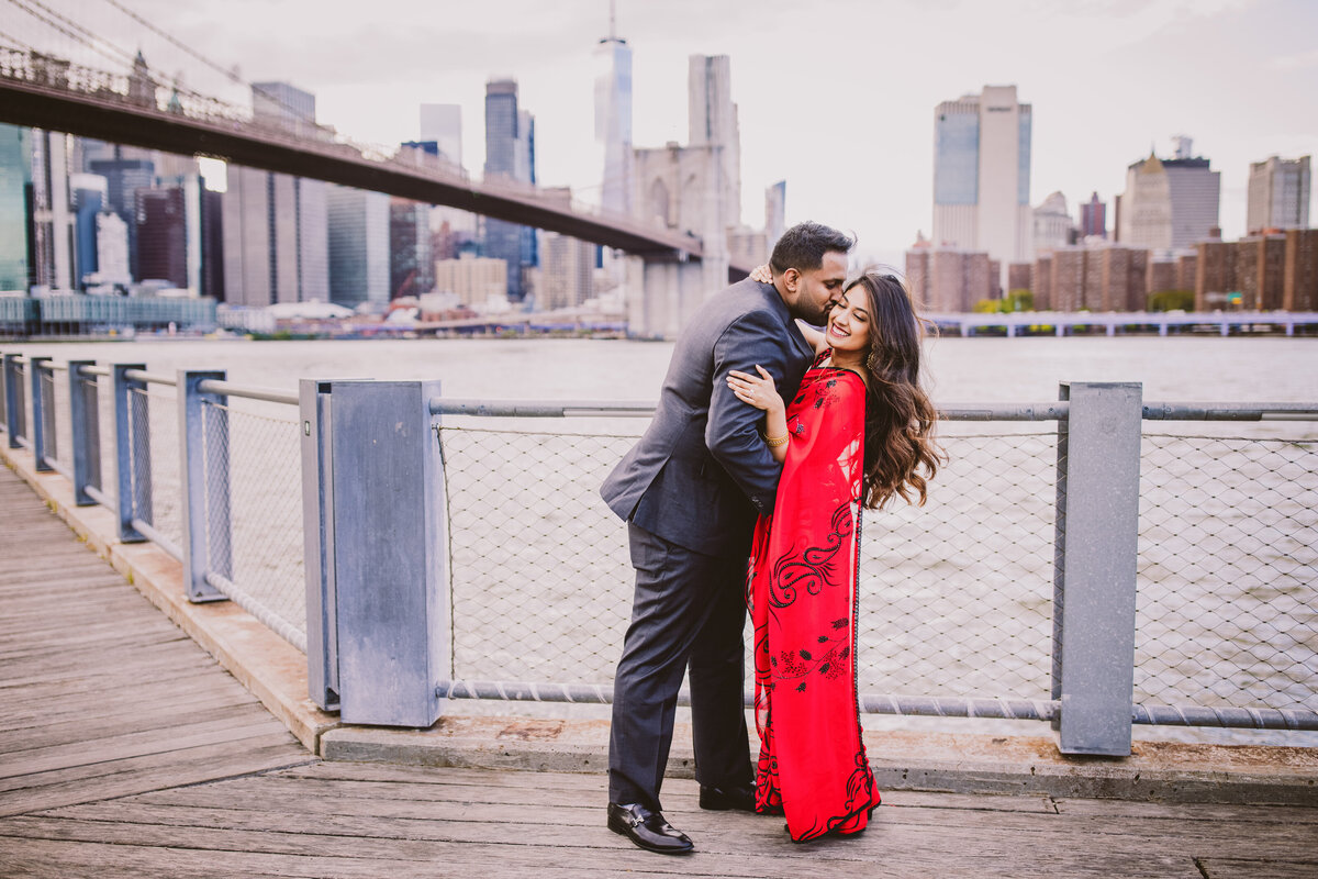 A couple kissing at the pier near the carousel at brooklyn bridge park in nyc