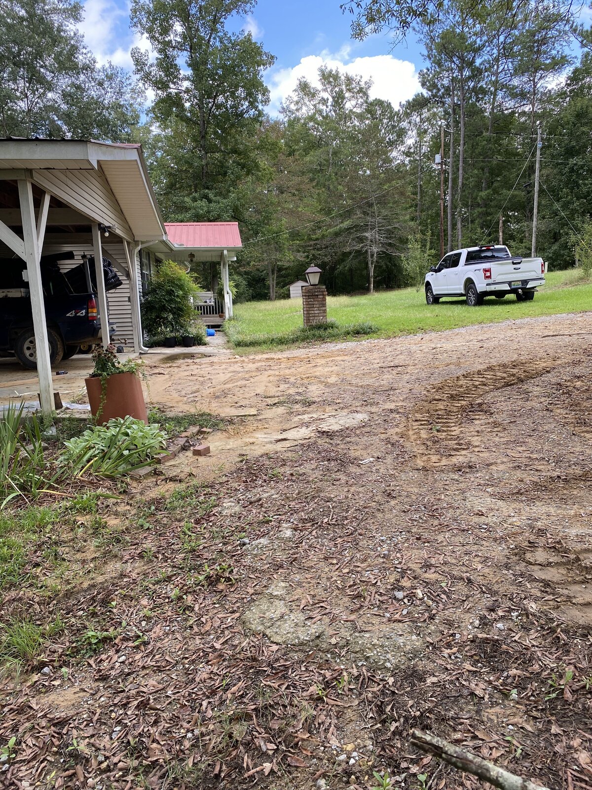 white-truck-parked-next-to-house-and-dirt-driveway