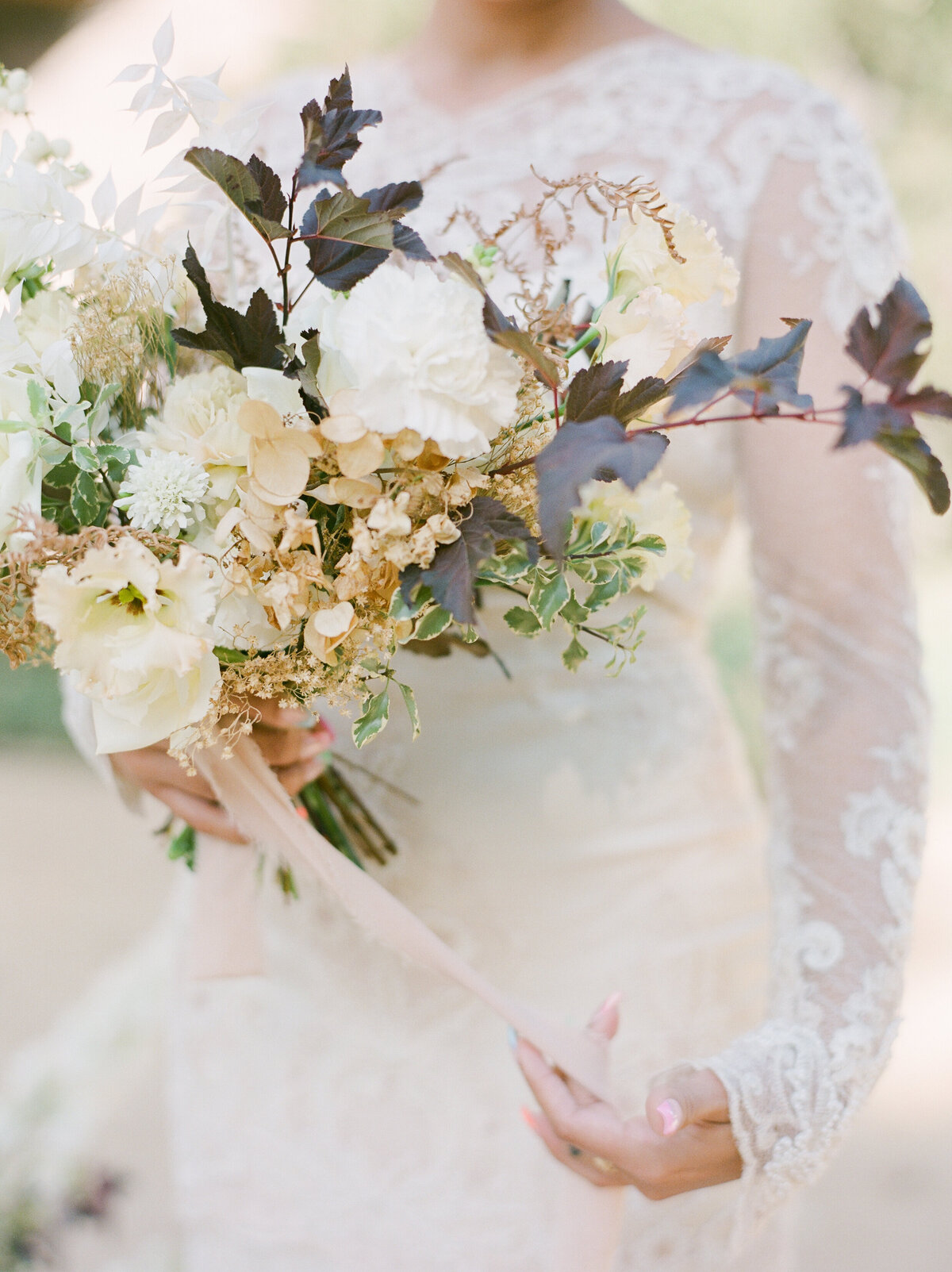 a bride holding a white bouquet of flowers and long silk ribbon