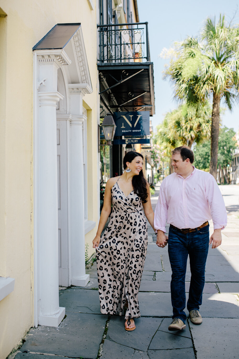 Engaged couple walking down uptown Charleston during their engagement photoshoot.