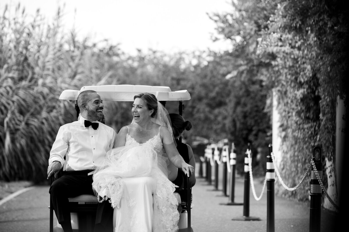 A bride and groom riding in a golf cart.