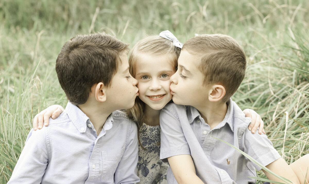 two brothers  kiss their sisters cheek