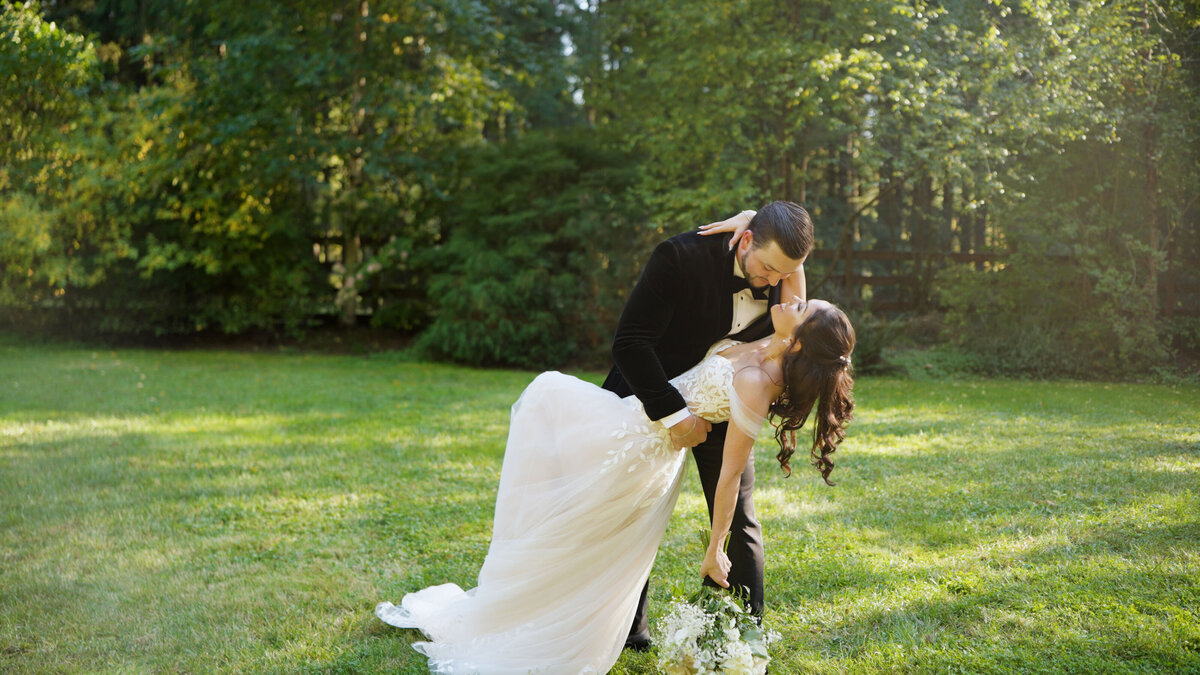groom dipping bride back while standing in a field
