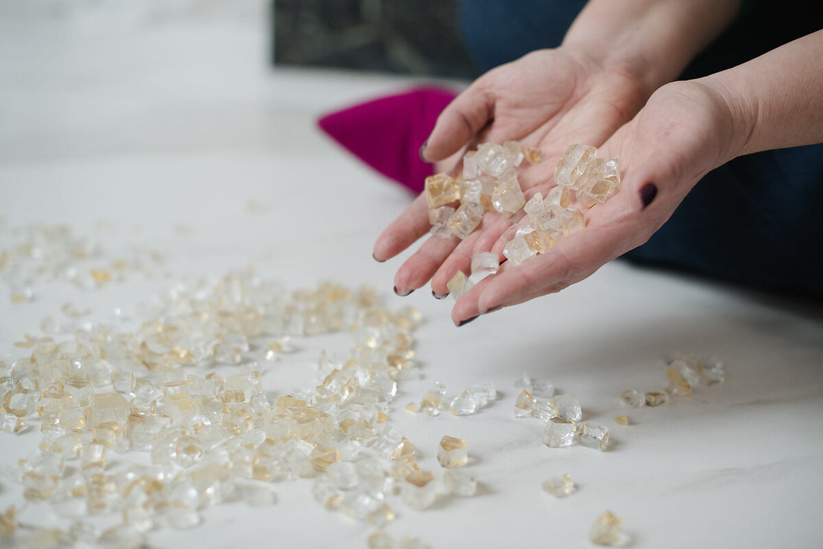 Woman's hands pouring broken glass onto marble floor