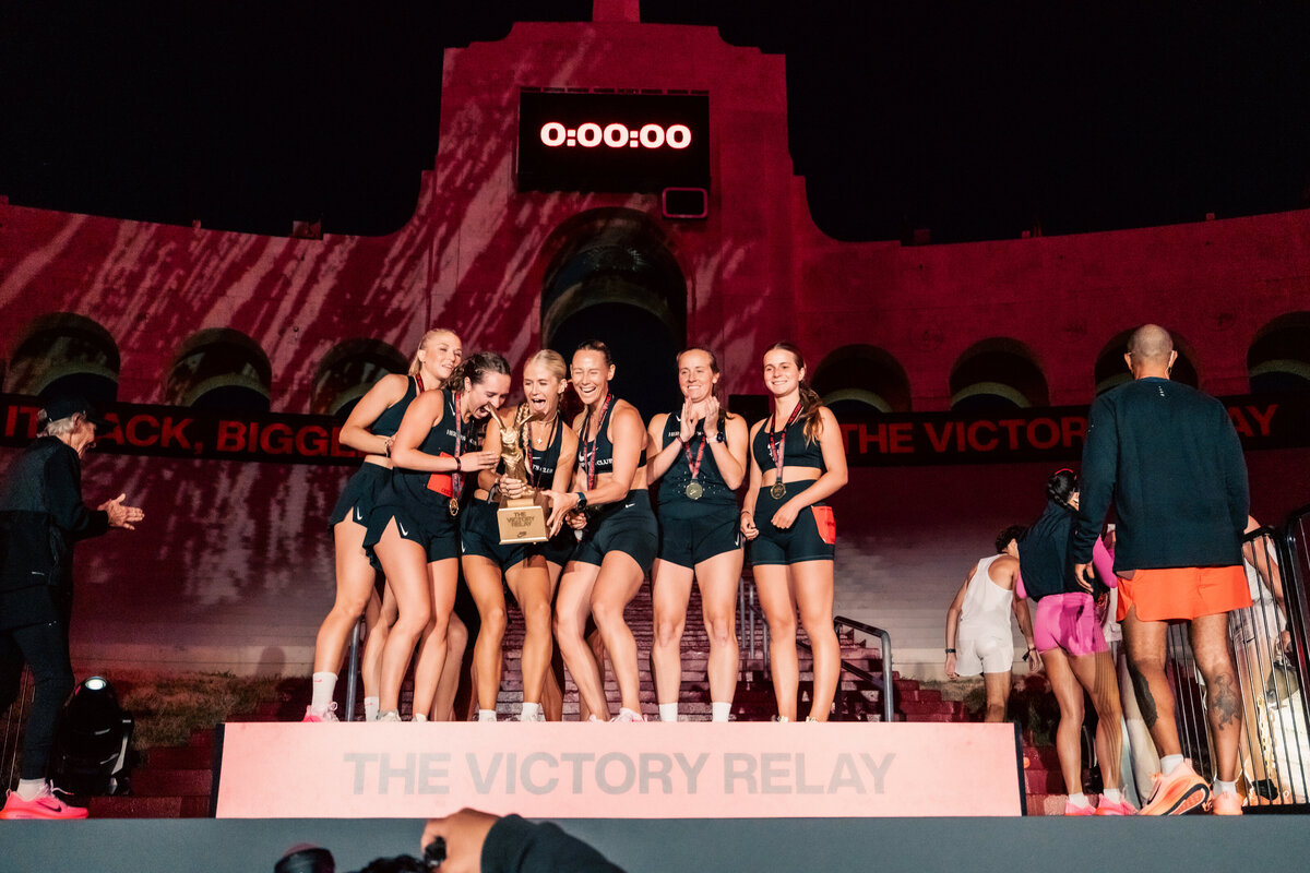 HER Sports Club women’s team celebrating on the Victory Relay podium after completing the race.