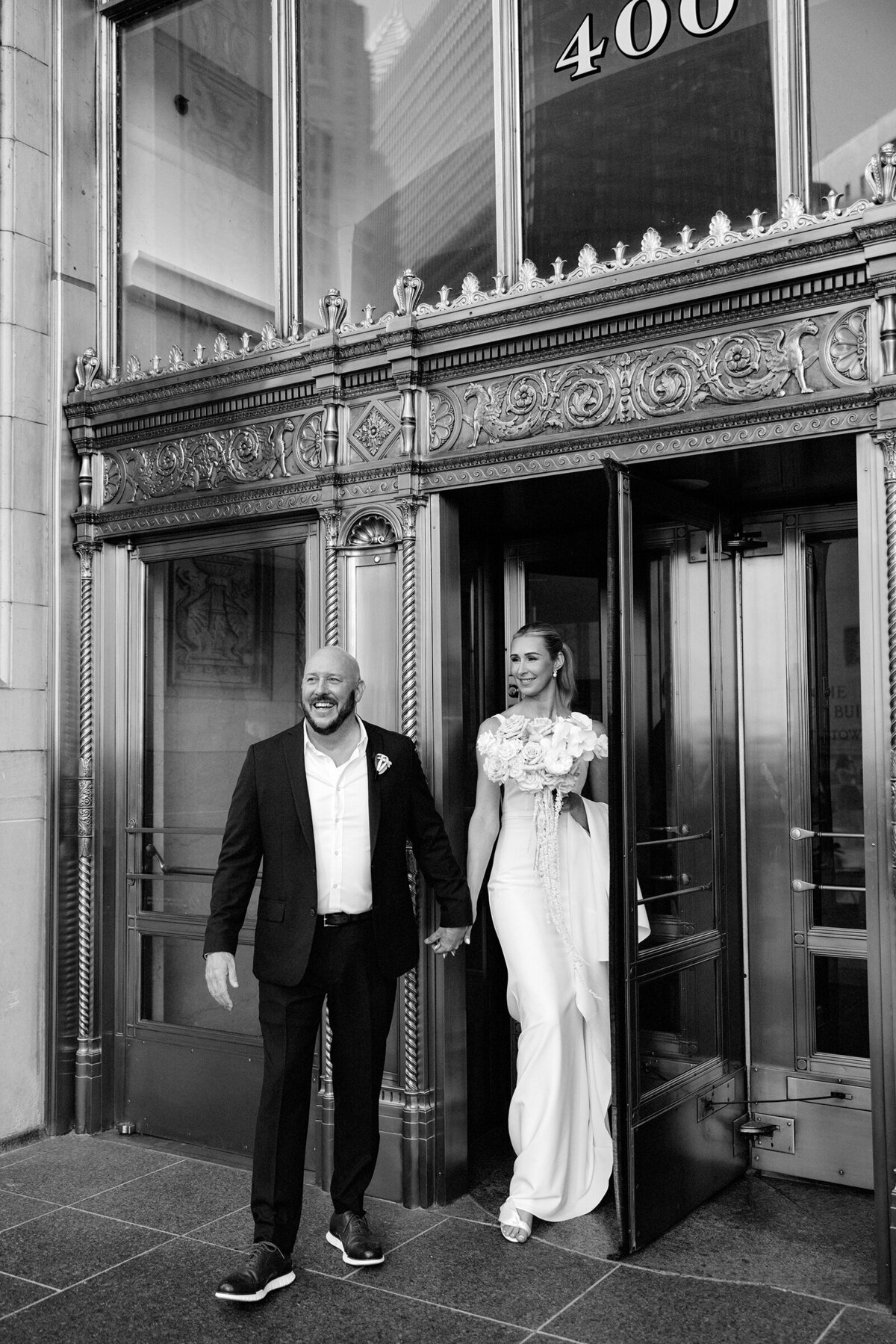 Black and white photojournalistic image of newlyweds in Chicago walking through revolving doors