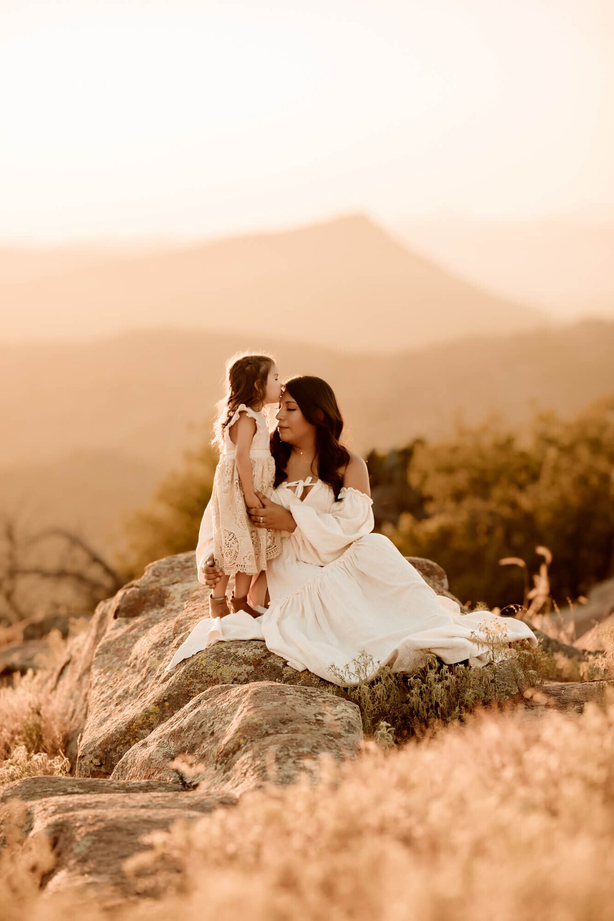 Little girl kisses her mother's head on top of the Wichita Mountains.