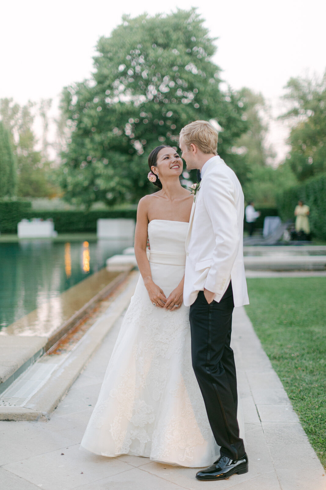 Bride and groom sharing a romantic moment by reflecting pool during luxury wedding in Provence.